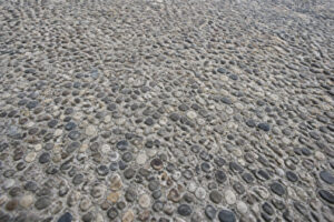 Texture en gros plan d'un revêtement de sol en béton désactivé composé de petits graviers arrondis.
